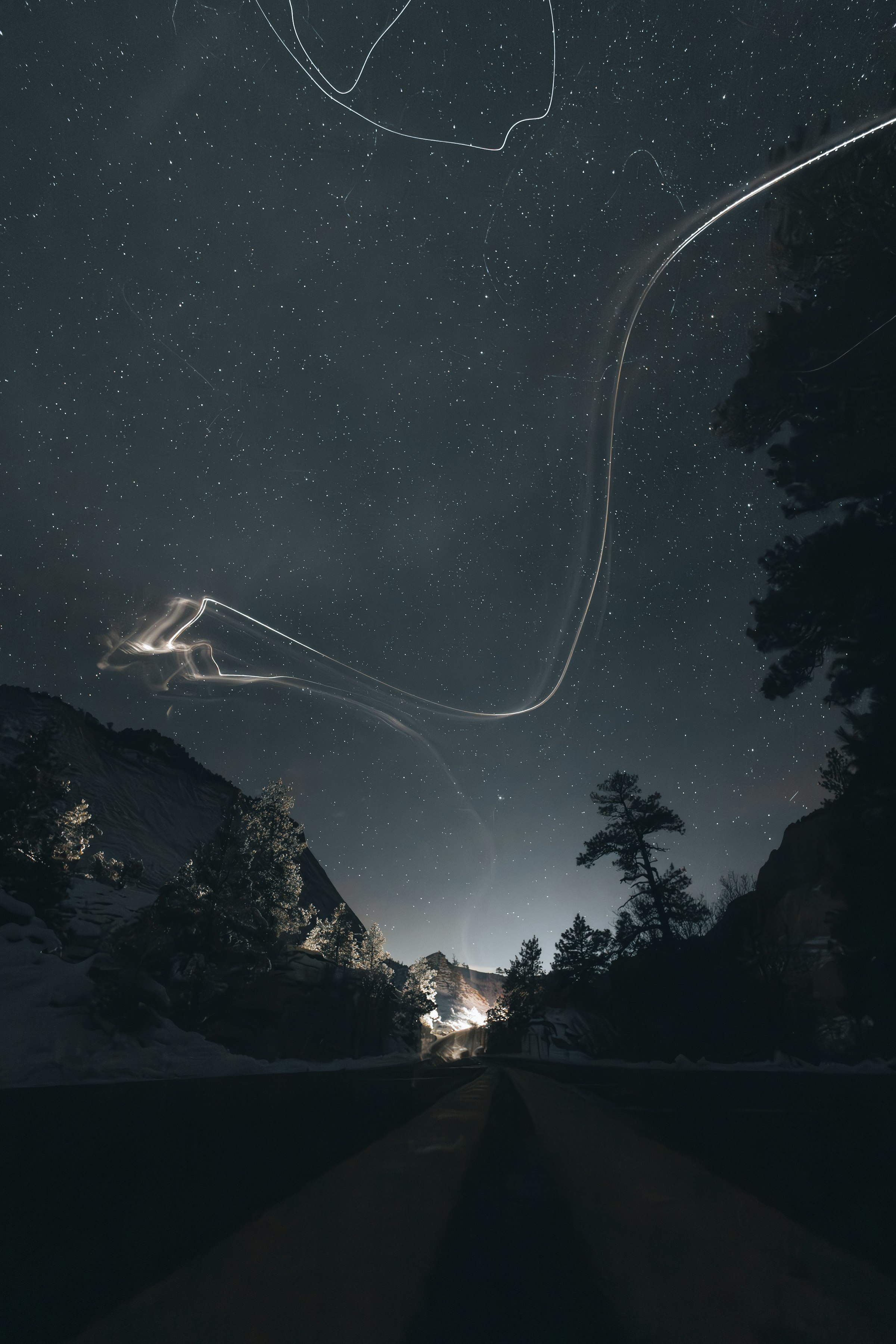 Light trails across a starry night sky over mountains by Florian Schindler